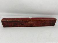 Closed view of original red box showing heavy wear and gold lettering faded but legible.