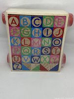 Front view of wooden alphabet blocks in natural wood frame with colorful letters from A to Z.