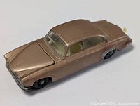 Side view of a bronze colored die cast Jaguar toy car showing compact shape and condition.