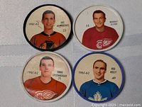 Four vintage Sherriff hockey coins featuring NHL players from 1961-62 season: Eric Nesterenko (Chicago Blackhawks), Murray Oliver (Detroit Red Wings), Eddie Litzenberger (Detroit Red Wings), and Red Kelly (Toronto Maple Leafs). Each coin shows player image, team logo, name, and number.
