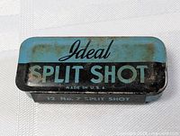 View of rectangular blue and black metal tin with Ideal Split Shot branding and Made in U.S.A text on lid. Shows signs of surface rust and light wear.