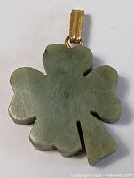 Front view of green jade four leaf clover pendant with gold-colored bail on top