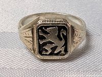 Front facing view of a silver ring with a black inset displaying a raised lion emblem.