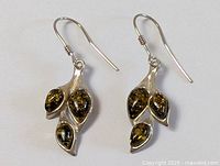 Pair of sterling silver earrings with three amber stones each in leaf shapes, shown side-by-side on a white background.
