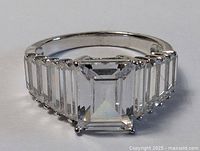 Front angled view showing the emerald-cut center stone and the baguette-cut stones extending along the shoulders.