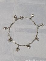 Full view of the sterling silver heart charm bracelet laid flat showing the overall design.