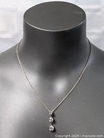 Front view of sterling silver necklace displayed on black bust, showing pendant with three clear stones in vertical arrangement.