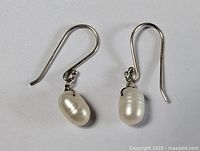 Pair of sterling silver earrings with white oval freshwater pearls, showing front view of both earrings side by side.