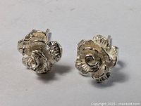 Close-up view of sterling silver rosebud earrings showing detailed petal texture and overall shape.