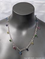 Sterling silver necklace with multicolored stone charms, displayed on a black mannequin, showing front and side views.