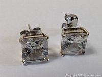 Close-up photo of one sterling silver stud earring with square cut clear gemstone showing front and side details.