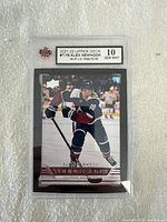 Front view of an Alex Newhook Young Guns card graded Gem Mint 10 by KSA in protective casing.