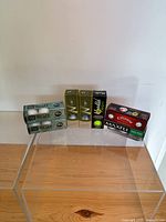 7 sleeves of assorted new golf balls on a clear display stand, showing all brands