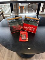 Photo showing the two Coca Cola metal bottle buckets and the mini playing cards set on a black table.