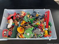 Top view of plastic container filled with assorted Lego pieces and mini figures.
