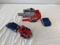 Optimus Prime figure parts laid out on a white surface, showing main cab and trailer separated with extra parts.