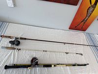Full view of three vintage fishing rods laid out horizontally on a white surface, displaying their length and types.