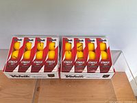 Two full boxes of Volvik ViMax Soft golf balls on clear display shelf, showing 24 yellow balls in total.