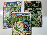 Photo showing three vintage Green Lantern comic books with colorful covers and visible wear, arranged fan-like.