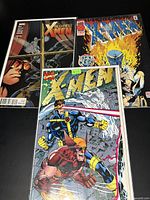 Three 1990's X-Men comic books laid out showing colorful covers and titles
