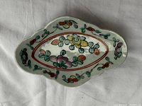 Top view of the uniquely shaped antique Chinese porcelain plate with colorful floral designs in the center and along the edges.