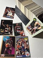 Box with approximately 300 basketball cards fanned and displayed on table with multiple notable cards spread out showing player images and branding.