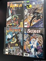 Four vintage Batman comics laid out, showing different cover artworks featuring Batman, Catwoman and other figures.