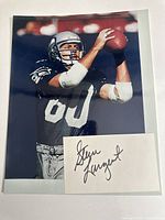 Photo of the Steve Largent football action photo with separate autographed paper in front.