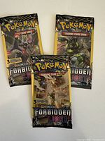 Three sealed Pokemon Sun & Moon Forbidden Light booster packs showing front artwork with Necrozma.