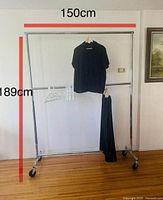 Full view of large double-layered stainless steel hanger against a wall showing dimensions 189cm height and 150cm width, with clothes and hangers displayed on it.