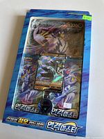 Front view of unopened box showing oversized holographic Rapid Strike Urshifu VMAX card and a holographic Urshifu V card inside the box along with booster packs.
