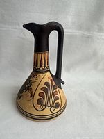 Full view of vintage Greek jug showing overall shape, decorative motifs, and dark neck and handle.