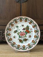 Front view of the decorative Chinese plate showing full design on wooden background.