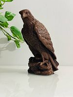 Front view of wooden eagle statue showing detailed feathers and rock base.
