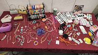 Wide view of all costume jewelry, purses, and hair accessories laid on burgundy cloth