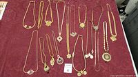 Full overview of costume jewelry lot on red fabric background showing all necklaces arranged parallel and spread out