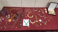 Wide overview of all jewelry laid out on burgundy cloth
