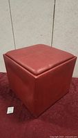 Photo of red leather cubic foot stool showing overall shape and upholstery.