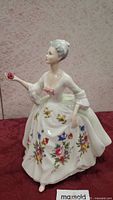 Front and side view of Royal Doulton Diana figurine showing floral decorated dress and pose with rose in hand.