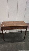 Front view of rustic vintage wooden side table with three small drawers and turned legs