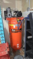 Front view of orange ProAir II vertical air compressor showing tank, motor and branding