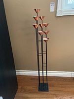 Full view of the tall metal candle holder with multiple copper-colored cups for tea lights.