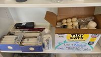 Shelf with candle boxes, bottle of candle additive, and tea light candles in reused cat litter box
