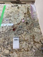 Wide view of costume jewelry lot showing multiple necklaces, bracelets, earrings arranged on granite countertop.