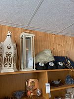 Shelf showing four black solar garden spotlights and folded beige bug jacket