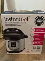 Front view of Instant Pot box showing image of pressure cooker, features, and brand.