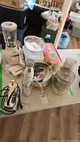 Overview of lot showing Rival hand blender, Osterizer blender, Oster steamer, Black & Decker food processor and cords on a table.