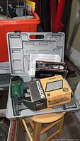 Photo of the lot contents showing the nailer, boxes for the filter and nails, and the storage case.