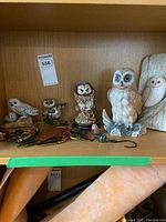 Shelf with multiple owl figurines including ceramic and metal bird decorations
