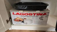 Lagostina extra large roasting pan box with black speckled broiler pan placed on top.